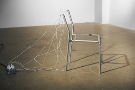Your Silent Listener, apple charging cords, aluminum, audio (plays "(I Just) Died In Your Arms" by Cutting Crew on repeat through the legs of the chair at "grocery store volume"), 2019.